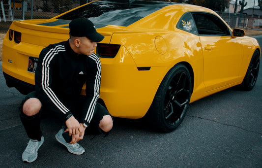man wearing black an white adidas long-sleeved shirt beside yellow coupe