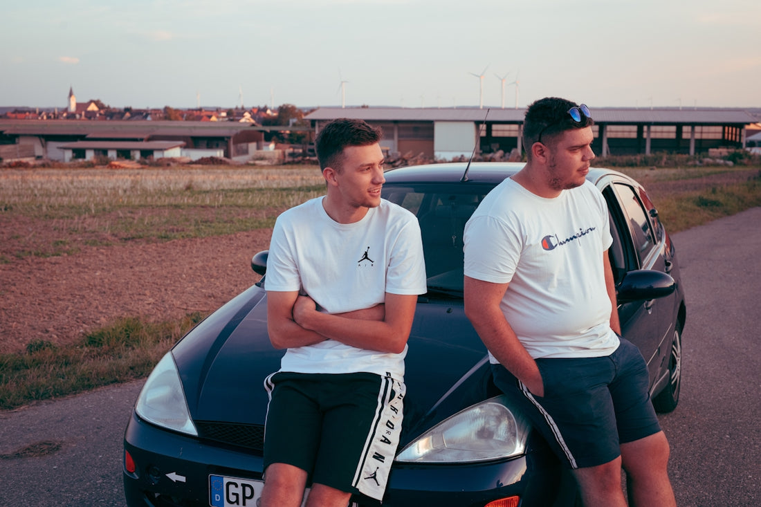 2 men in white crew neck t-shirt standing beside blue car during daytime