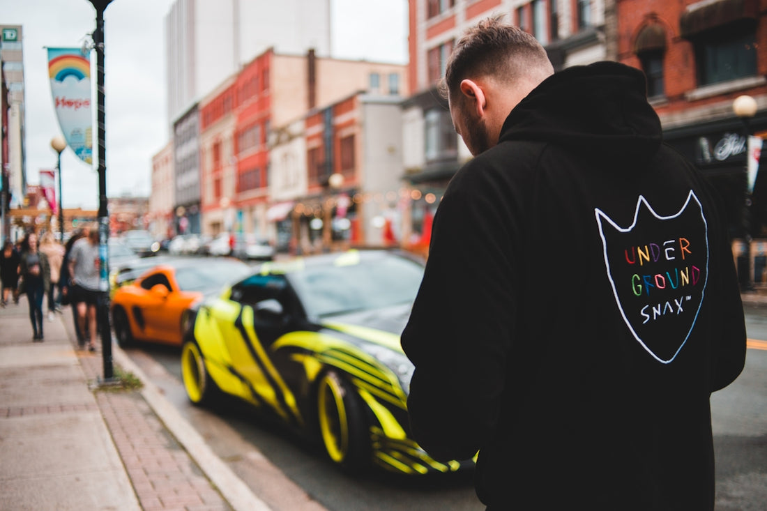 man in black hoodie standing on the road during daytime