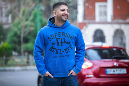 man in blue and white pullover hoodie standing near red car during daytime