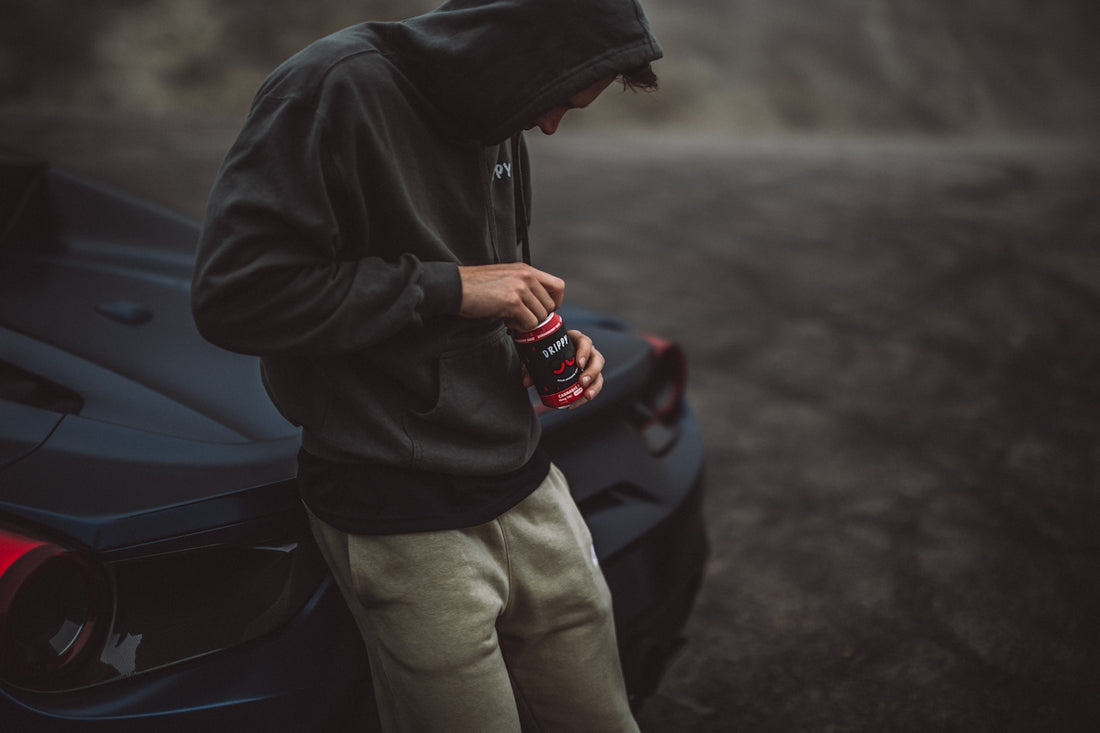 a man standing next to a sports car looking at his cell phone