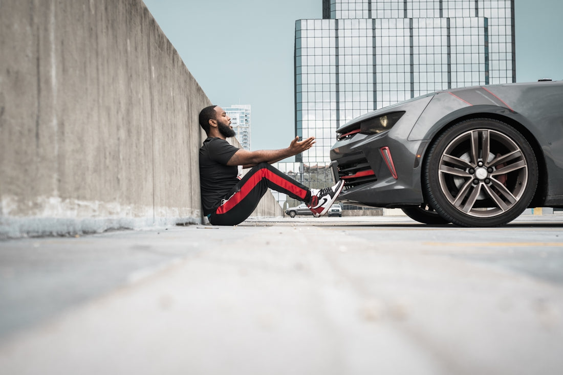 a man sitting on the ground next to a car