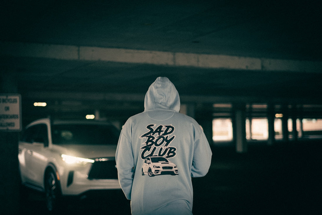 a person in a hoodie standing in a parking garage